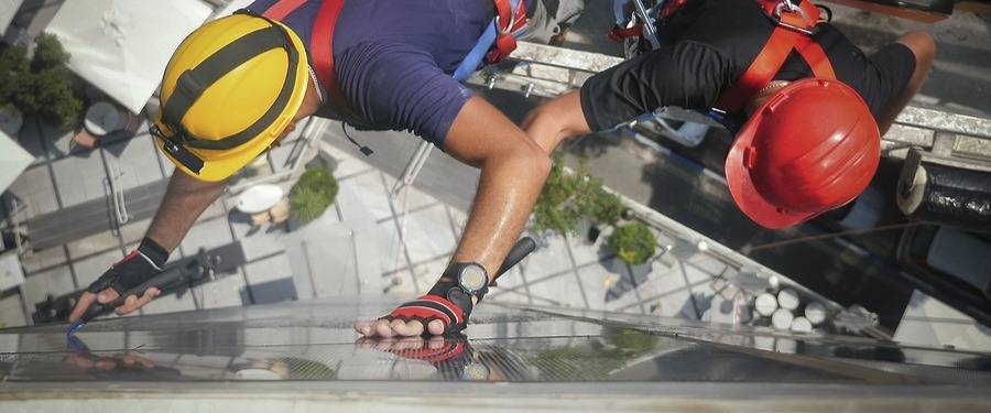 A team of scaffolding experts inspects a window at high elevation from suspended scaffolding.